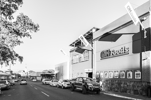 Prieska, South Africa - Feb 28 2023: A street scene, with a supermarket, people, vehicles and a church, in Prieska in the Northern Cape Province. Monochrome