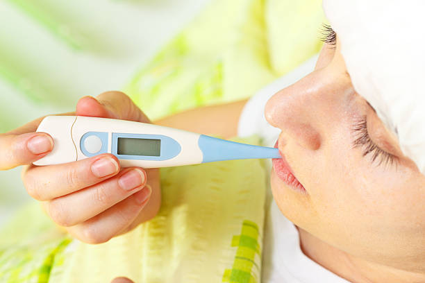 istock Woman being ill in bed and measuring temperature 148998229