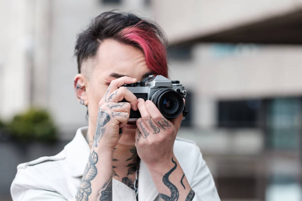 istock Front portrait of alternative non-binary male model using film camera. 1489982665
