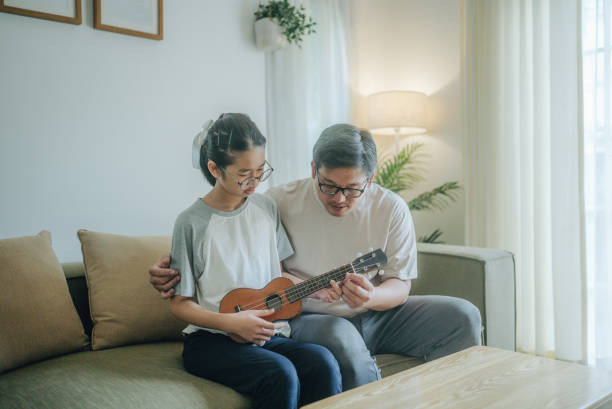istock Asian father Playing Guitar during coffee break time. Daughter sitting beside and spending wonderful time with him 1489986701