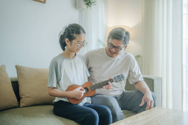 istock Asian father Playing Guitar during coffee break time. Daughter sitting beside and spending wonderful time with him 1489987243
