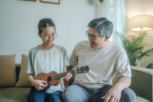 istock Asian father Playing Guitar during coffee break time. Daughter sitting beside and spending wonderful time with him 1489987251
