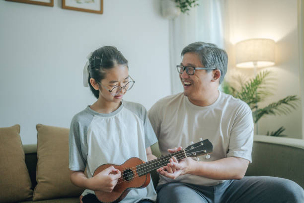 istock Asian father Playing Guitar during coffee break time. Daughter sitting beside and spending wonderful time with him 1489987270