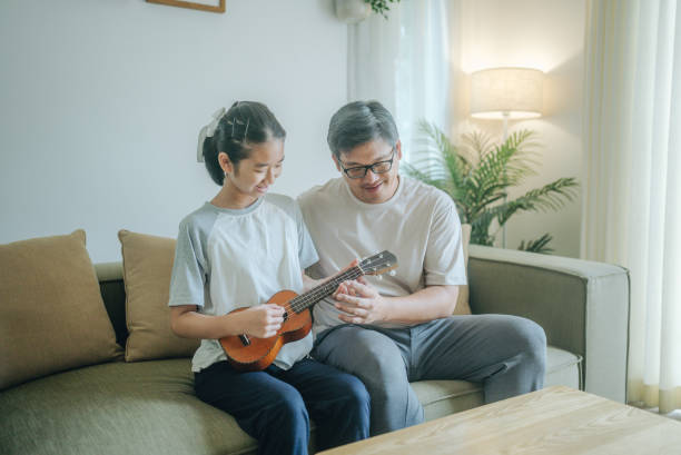 istock Asian father Playing Guitar during coffee break time. Daughter sitting beside and spending wonderful time with him 1489987295