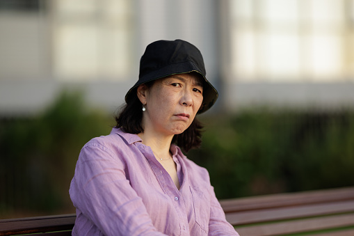 Woman sitting outdoors with an annoyed expression in the late afternoon.