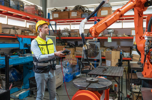 istock Male automation engineer testing new robot arm welding machine by using laptop control for operating at industrial factory 1489992137