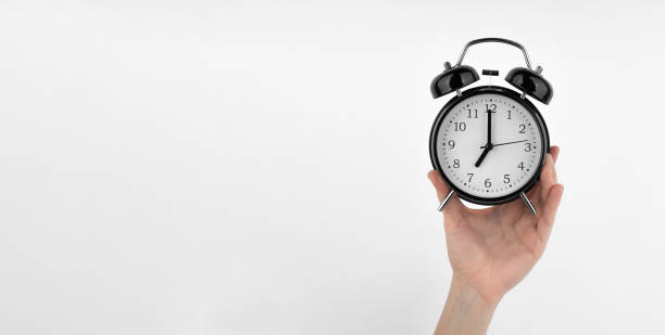 istock Isolated woman's hand holds a black alarm clock 1489992933