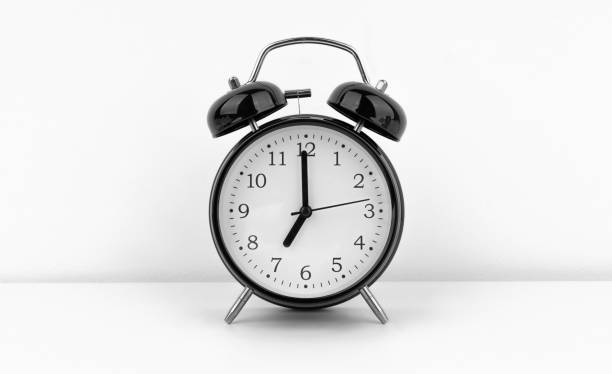istock Black alarm clock on white wall background 1489992941