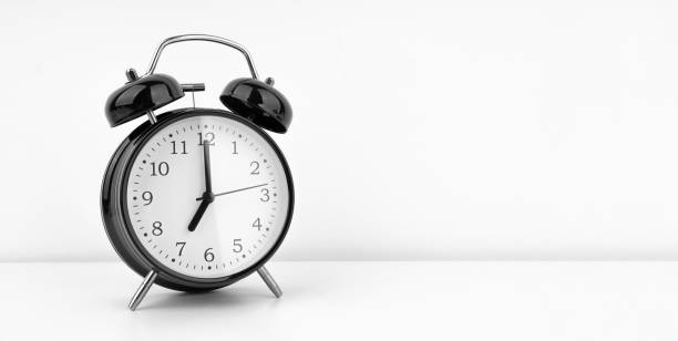 istock Black alarm clock on white wall background 1489992945
