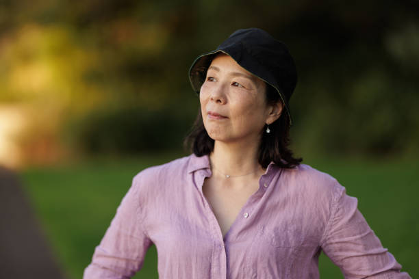 femme asiatique avec chapeau à l’extérieur, regardant au loin - women thinking contemplation sideways glance photos et images de collection