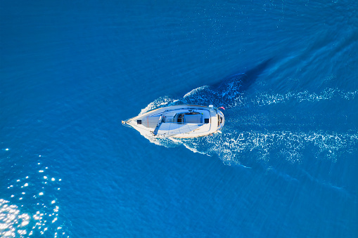 Wave and sail yacht on the sea as a background. \nSea and waves from top view. Blue water background from top view. Top view from drone. Summertime vacation. Travel image