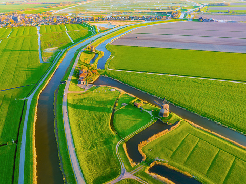 An aerial view of the windmill. Canals with water for agriculture. Fields and meadows. View from a drone. Landscape from the air.