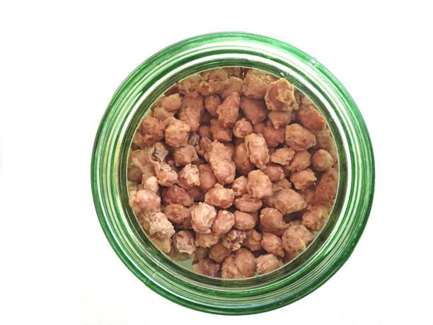 istock Bunch of Coated Fried Peanuts in A Glass Jar Container on White Background 1490001632