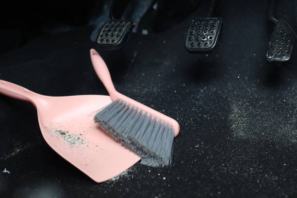 use broom and trash shovel to clean in the carpet area under the accelerator pedal and car coupling stock photo