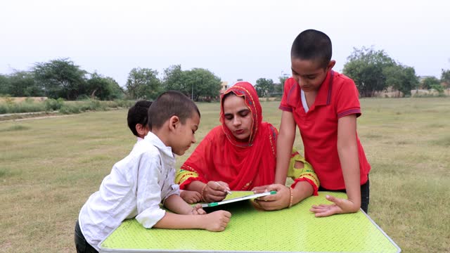 Indian mother teaching elementary children at home in garden