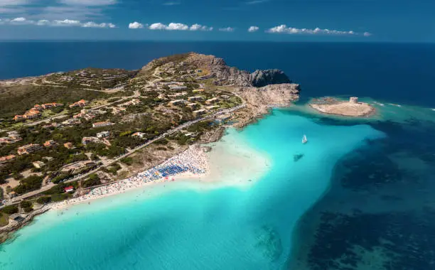 Top view of seascape with coastline and sandy beach with crowd people morning on sunny summer day. Sea coast with blue, turquoise  water, aerial view. Popular beach La Pelosa, Sardinia, Italy. Travel, holiday background