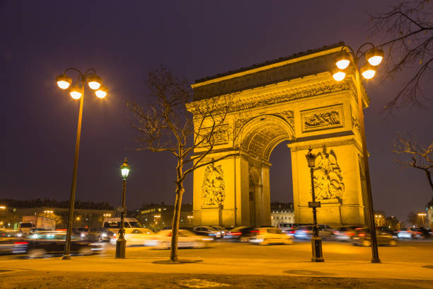 триумфальная арка этуаль на площади шарля де голля ночью в париже, франция - paris france night charles de gaulle arc de triomphe стоковые фото и изображения