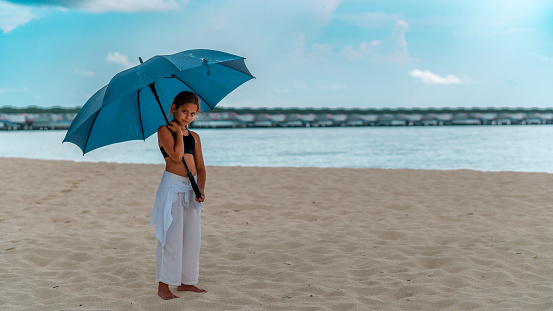 Little Beach Beauty: Adorable Girl Soaking up the Sun Under Her Umbrella