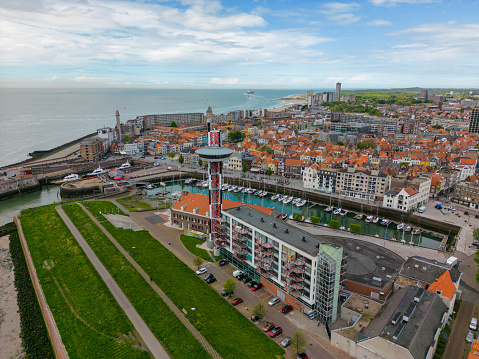 This aerial drone photo shows the harbour of the coastal city named Vlissingen, in Zeeland, the Netherlands. Some boats are in the Port, there is large tower and you can see the North Sea.