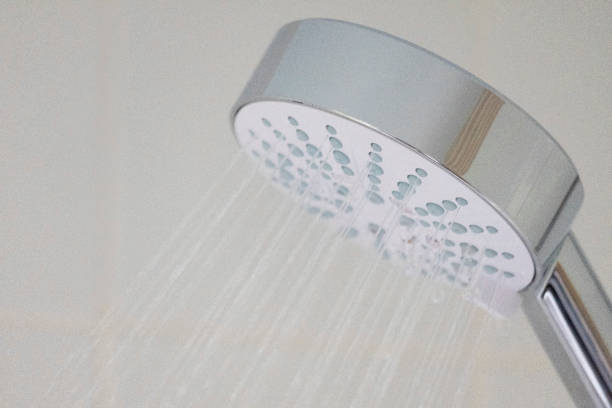 istock Shower Head with running Water Against White Tiles, Close up View 1490031744