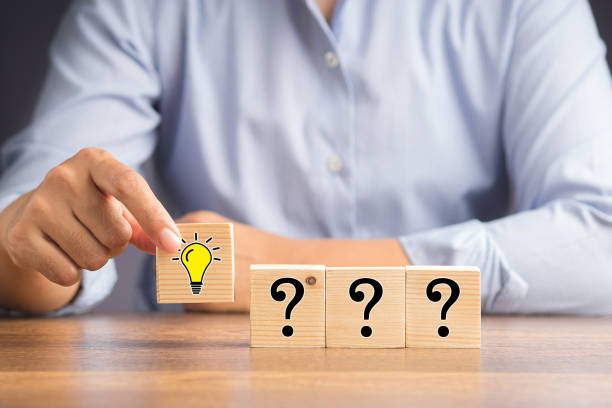 istock Hand holding a wooden cube with a drawn light bulb and a row of cubes with question marks 1490031766