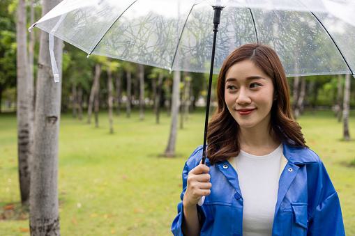Young Asian woman rainy walks with umbrellas in the public outdoor park