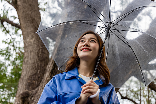 Young Asian woman rainy walks with umbrellas in the public outdoor park