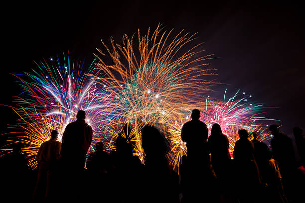 big fireworks with silhouetted people in the foreground watching - vuurwerk stockfoto's en -beelden