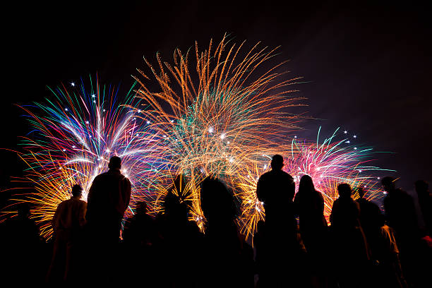 Big fireworks with silhouetted people in the foreground watching Big fireworks with silhouetted people in the foreground watching Pyrotechnics stock pictures, royalty-free photos & images