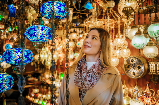Young cheerful woman choosing lamp on Grand Bazaar in Istanbul, Turkey