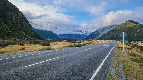 An empty State Highway 80 road towards Aoraki Town and Mount Cook flanked by grassland during early evening time. Shot taken during March.