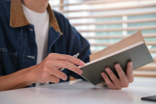 istock Cropped shot of man doing homework and writing in copybook. Education, e-learning concept. 1490061579