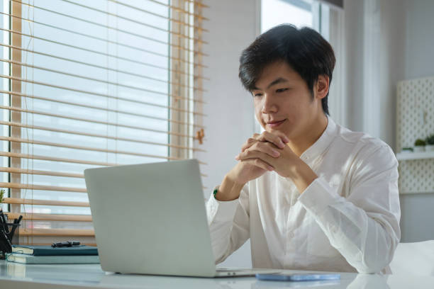 istock Handsome young businessman in white shirt reading email on laptop computer. 1490063564