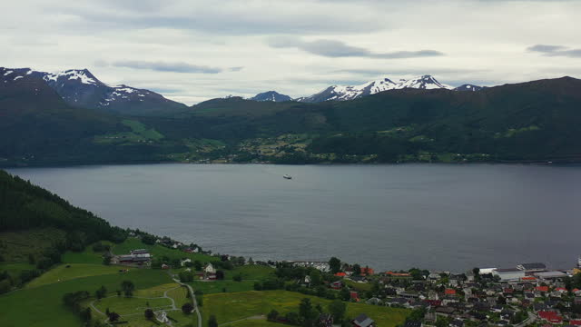 Aerial View of Small Town in Norway in Green Colours Surrounded by Lake and Mountains