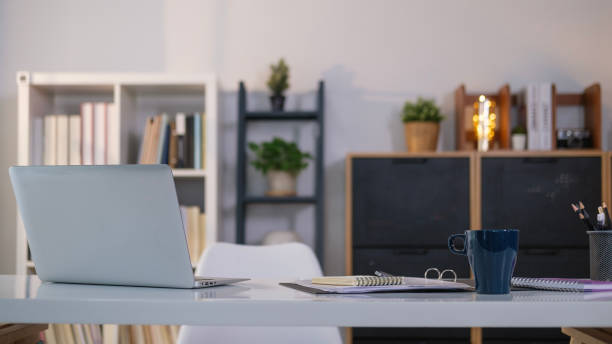 istock Simple workspace with laptop, notebooks, coffee cup and pencil holder on white table. 1490065819