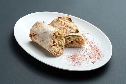 grilled pita roll with chicken, greens and cheese or shawarma sandwich on plate