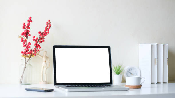 istock White working desk with laptop, coffee cup and books. Modern workspace, blank screen for your advertise text. 1490069458
