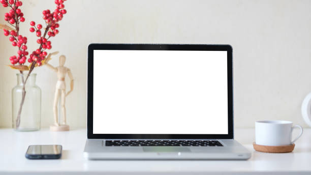 istock Close up view of laptop computer with blank screen, smartphone and coffee cup on white table. 1490069495