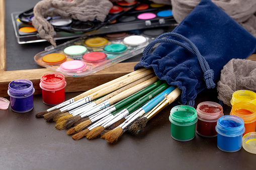 Paint brushes in composition with oil paints and watercolors.