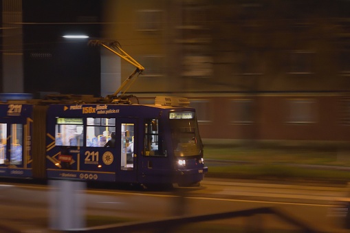 Ostrava, Czech Republic – November 24, 2022: A night shot of a public transportation vehicle moving along a street in a city, illuminated by street lights