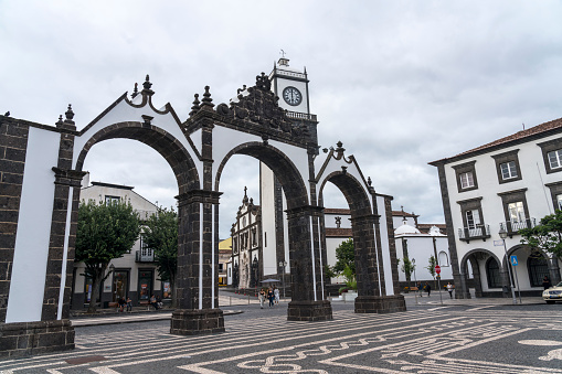 Portugal, Ponta Delgada - 29 September 2022: Portas da Cidade, the city symbol of Ponta Delgada in Sao Miguel Island in Azores, Some people on the street and at the restaurant. Portugal.