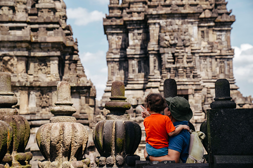 asian man carrying his son visiting prambanan temple, Yogyakarta
