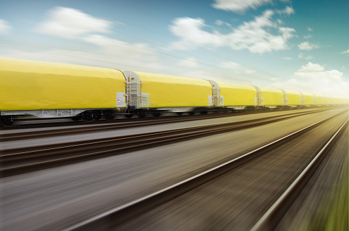 yellow cargo wagons are speeding on railroad platform. Motion blur and vanishing point.