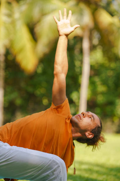 A man stretches his arm to the sky in a yoga pose stock photo