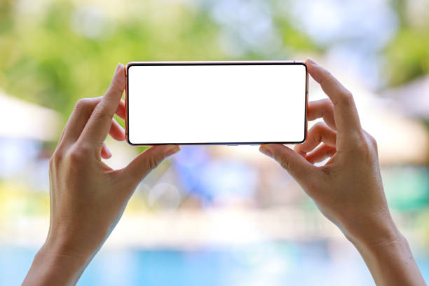 A mockup smartphone held by a woman against the backdrop of a tropical resort. This composition captures the essence of travel and outdoor recreation. It highlights the seamless integration of technology into our modern adventures and signifies the role of smartphones in enhancing our travel experiences. una maqueta de teléfono inteligente sostenida por una mujer en el contexto de un resort tropical. esta imagen representa viajes y recreación al aire libre. muestra cómo los teléfonos inteligentes se integran perfectamente en nuestras aventuras, mejoran