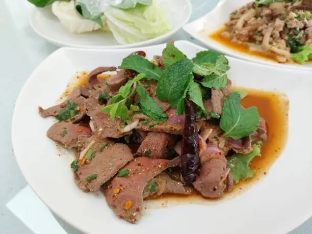 Photo of The favorite dish of Thailand, spicy pork liver salad (Tub wan) served with mint leaves and fresh vegetables.