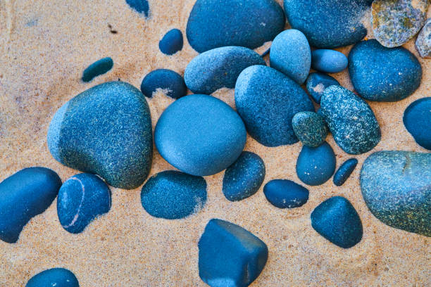 Image of Blue and black stones against a sandy beach