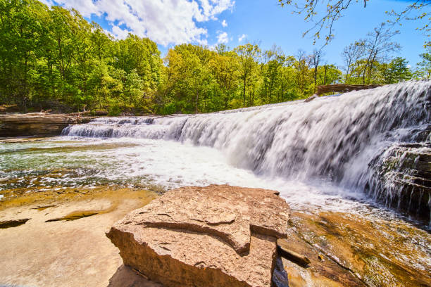 istock Boulder on coast with large waterfall and lush green forest in background 1490081820