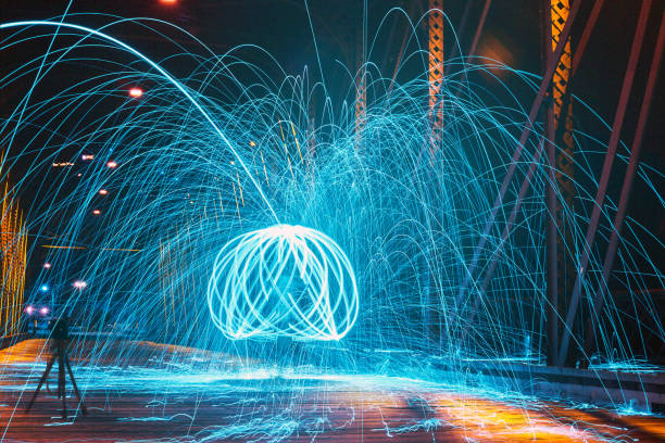 istock Bright blue sparks spinning in multiple circles around a man on a bridge at night 1490081952