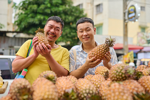 an asian malay fruit retail owner spraying his pineapples and getting ready for business